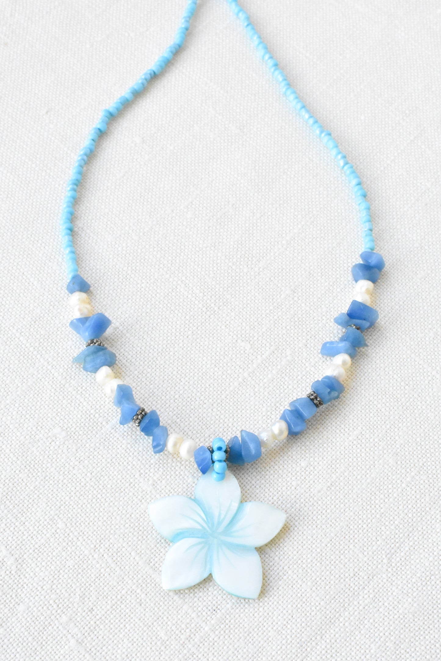 Flower pendant necklace with pearls, shell and blue gemstones