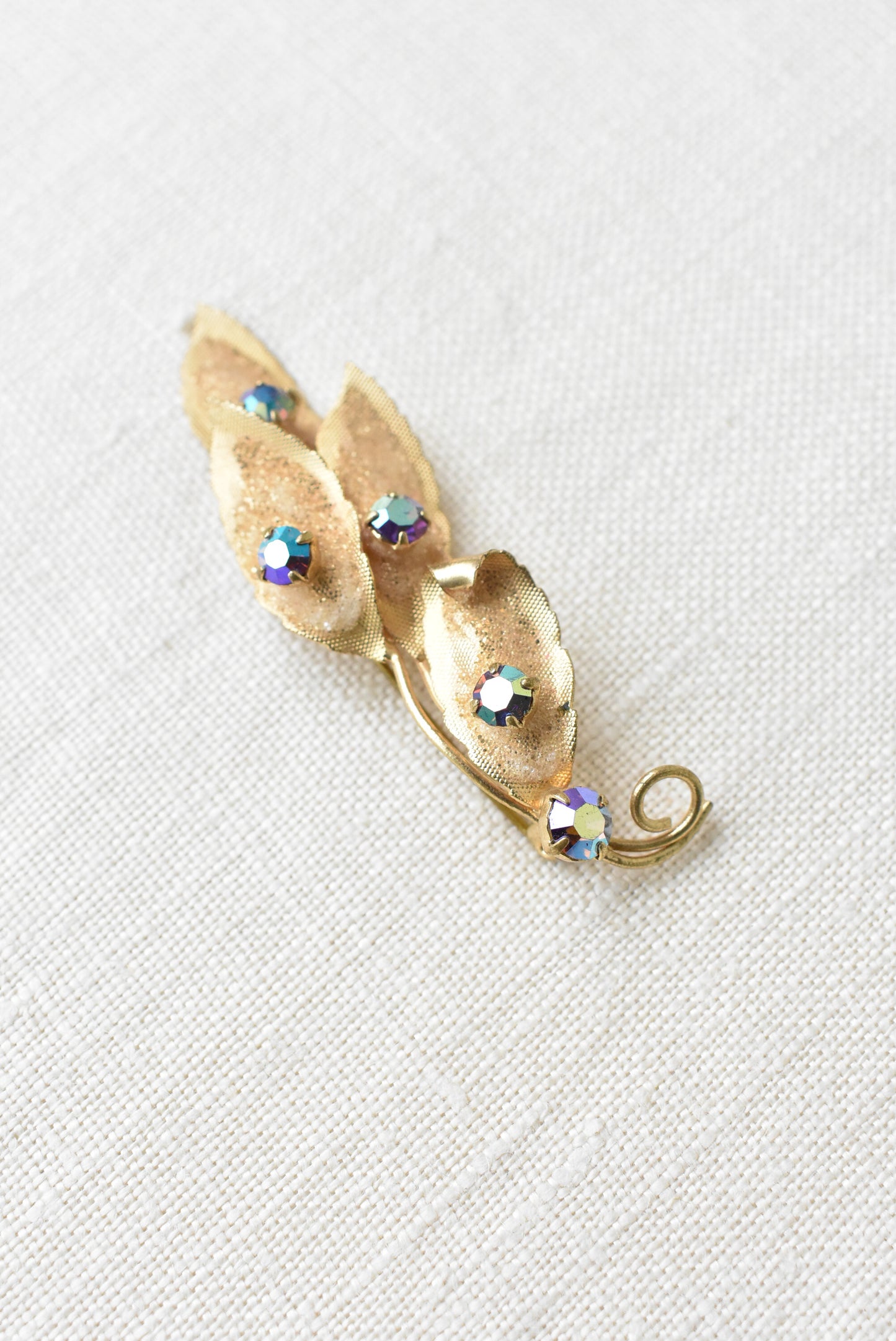 Glitery brassy molded leaf and diamante brooch