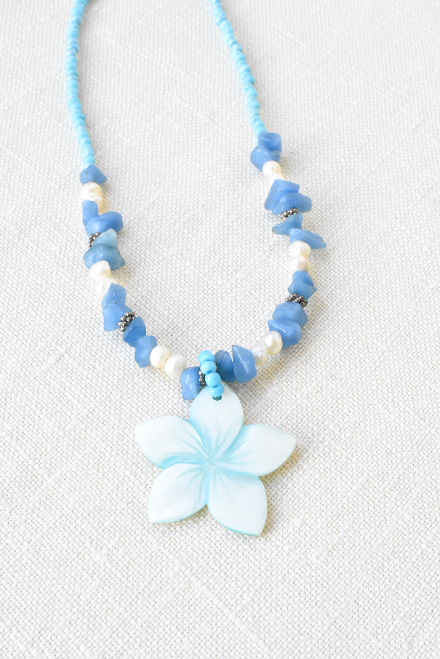 Flower pendant necklace with pearls, shell and blue gemstones